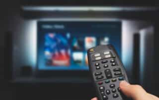 VOD service on television. Man watching TV, streaming service, video on demand, remote control in hand.